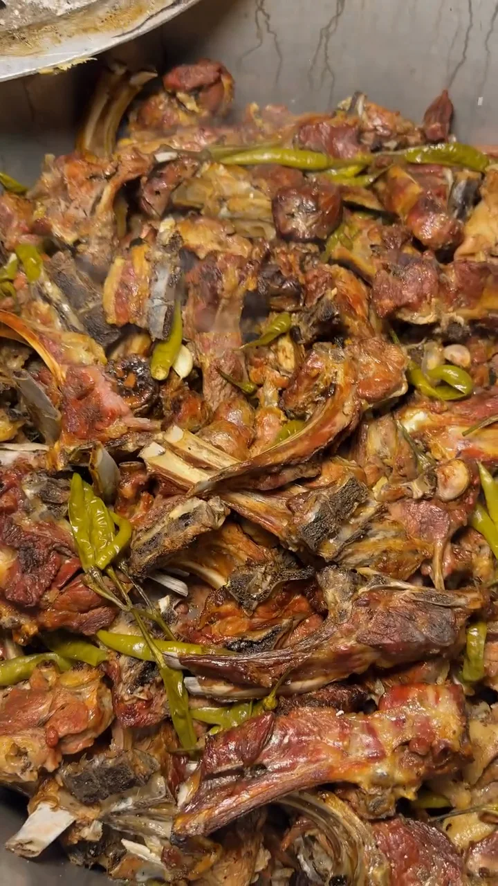 Cooked meat and green chillies in a large serving pan at Ghani Shinwari